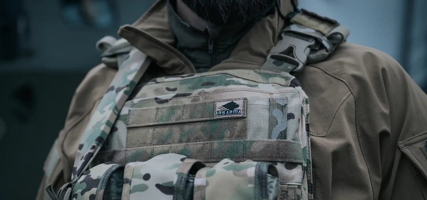 Person wearing a tactical vest with a camouflage pattern and visible logo Ars Arma on a blurred background
